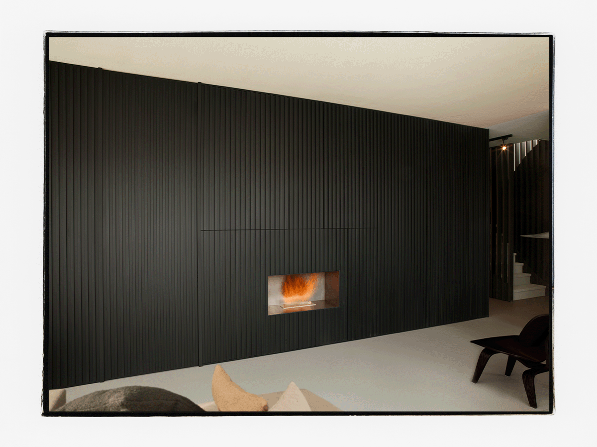 Raumhoher Raumteiler in schwarz mit integriertem Kamin und Stauraum